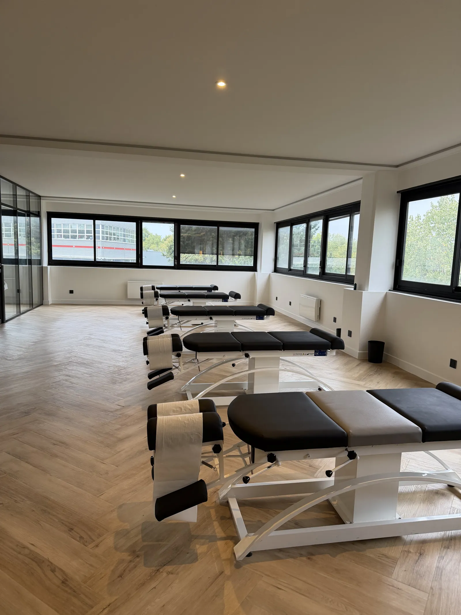 L'espace d'ajustements de l'office : tables chiropratiques noires et grandes fenêtres